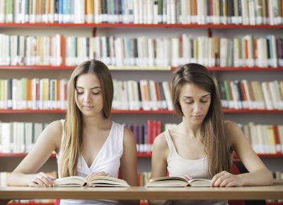 dwie uczennice uczą się w bibliotece